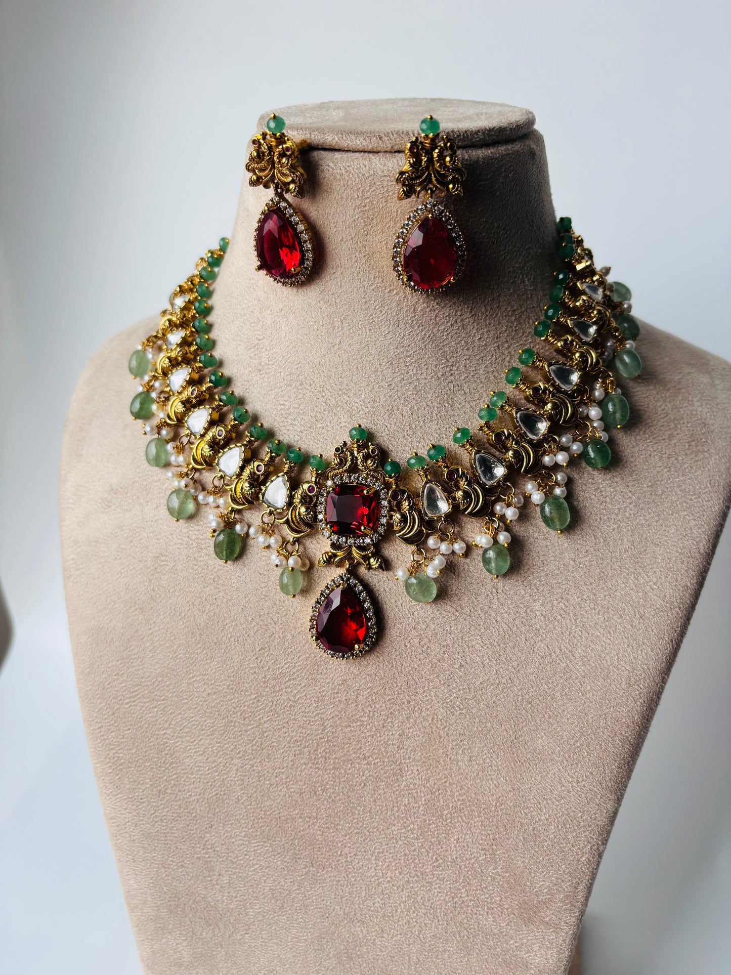 A stunning regal choker set adorned with ruby red stones, pearls, and emerald accents.