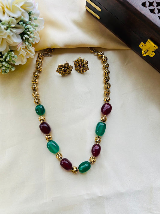 A timeless green/ruby gems and antique gold necklace set crafted to add effortless elegance