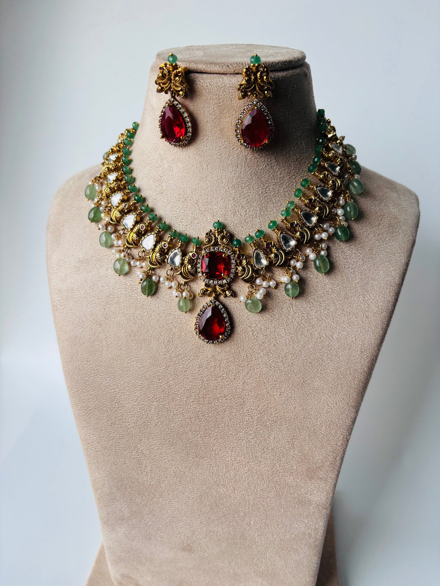 A stunning regal choker set adorned with ruby red stones, pearls, and emerald accents.